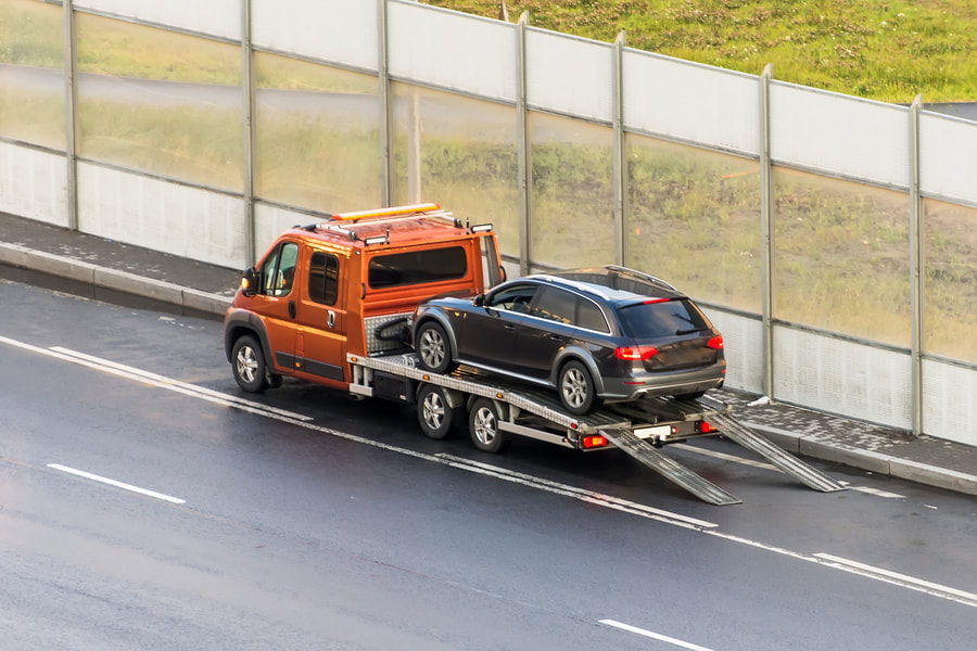 black car towed by flatbed truck